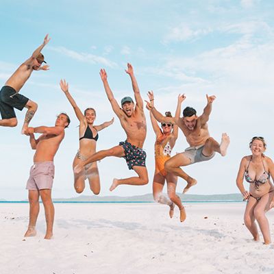 Group of backpackers jumping at the beach