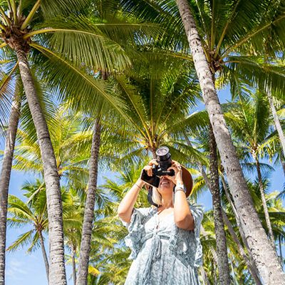 Woman taking a photo of palms and blue skies in Cairns
