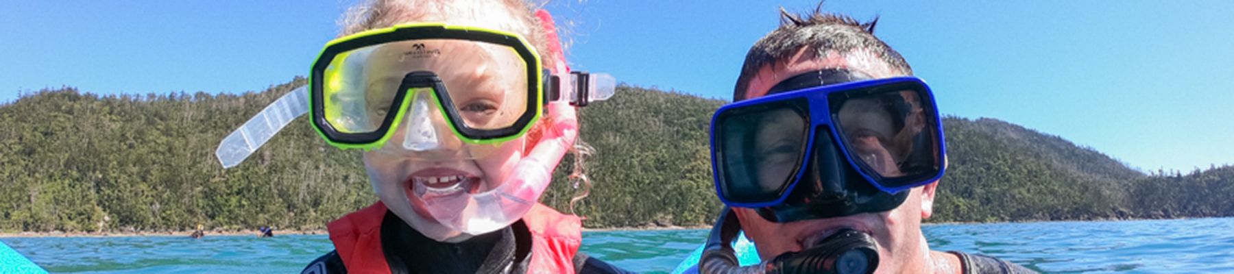 Father and daughter with snorkel gear on in the water