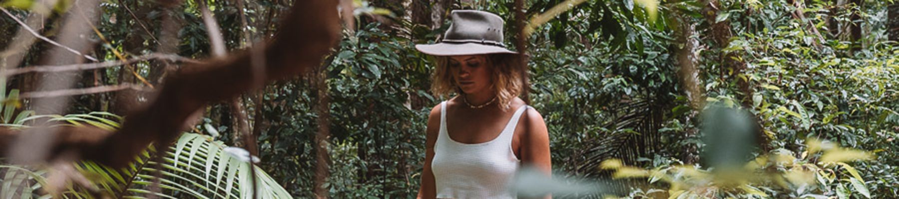 Woman walking through rainforest with white hat