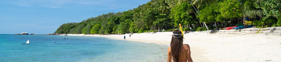 girl walking on fitzroy island beach with snorkel gear