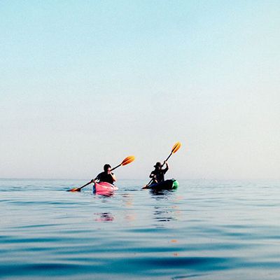 Two kayaks gliding through blue, calm water