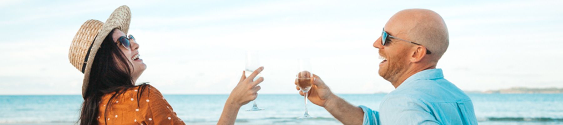 Two people laughing at each other holding up wine glasses
