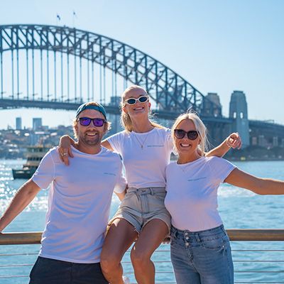 Three people sitting in front of the Sydney Harbour Bridge
