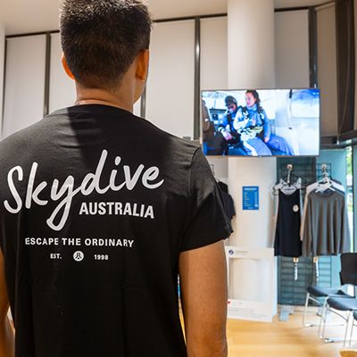 A man in a skydive aus tshirt and a safety briefing video