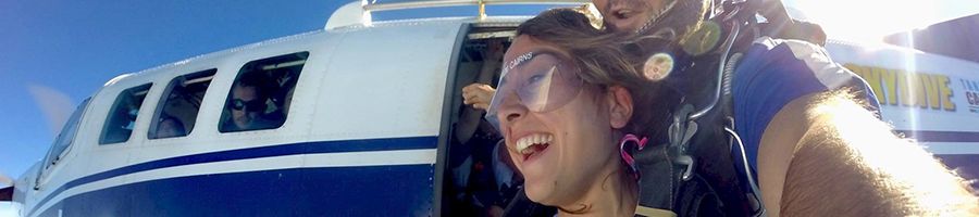 Women tandem skydiving, jumping out've the plane with instructor