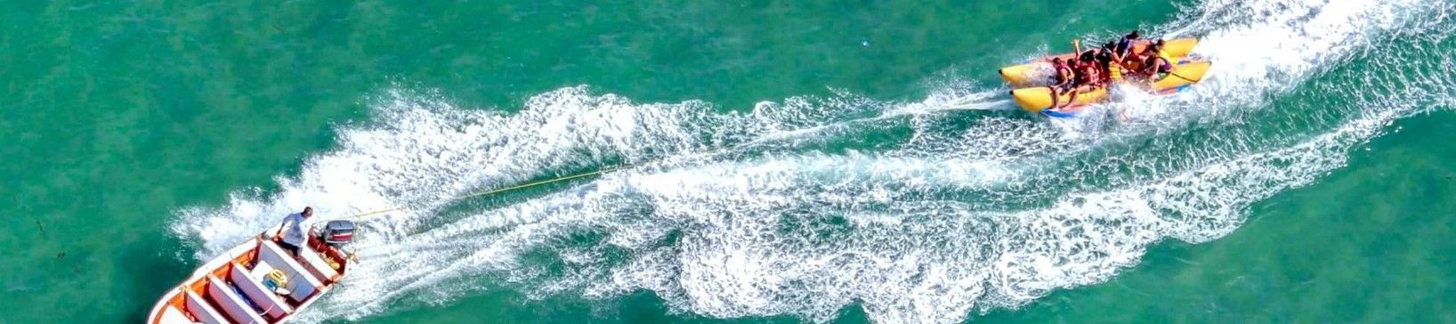 Banana boat zooming through blue waters, dragged by powerful jet ski, bird's-eye view
