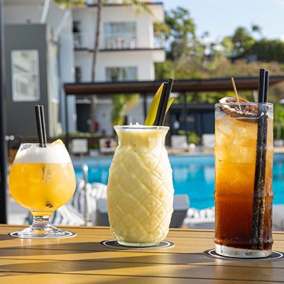 Three cocktails lined up by the pool