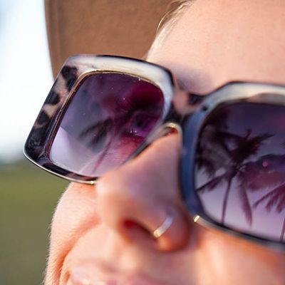 Woman with palm tree reflected sunglasses