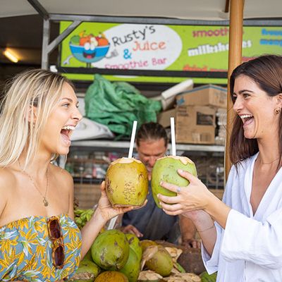 Cairns Fruit Market with two women cheersing a coconut