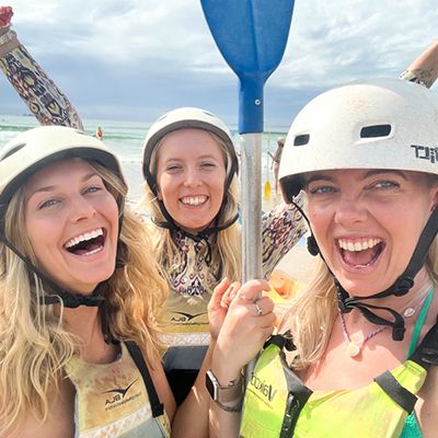 Three people with kayak paddles at the beach