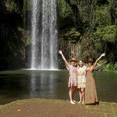 Waterfall in Cairns with three people smiling in front of it