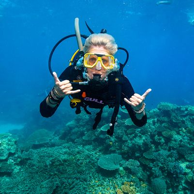 Scuba diver on the Great Barrier Reef throwing a 'shakkas'sign