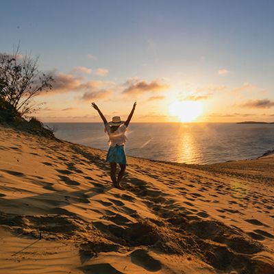 Woman with her hands in the air at the sandblow at sunset