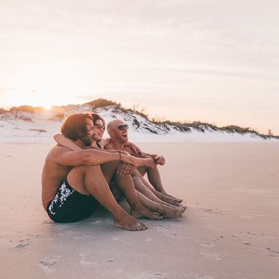 Three people on the sand laughing