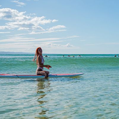 Women sitting on a paddleboard in the surf