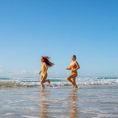Two women running through the ocean waves