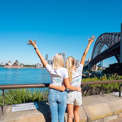 Two people in front of the Sydney HArbour Bridge and Opera House