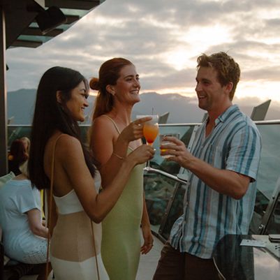 Three people having cocktails at a rooftop bar, Cairns
