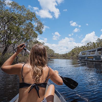 Canoeing through the Noosa Everglades with a cruise vessel in the background