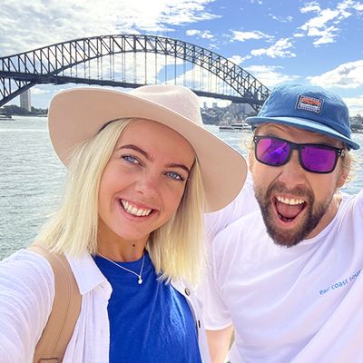 Two people in front of the Harbour Bridge with big smiles