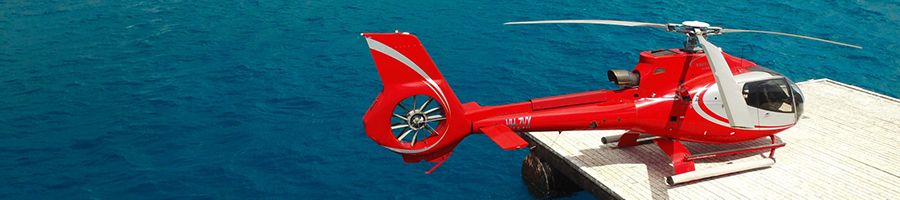 Red helicopter on a reef land pad at Hastings Reef, Cairns