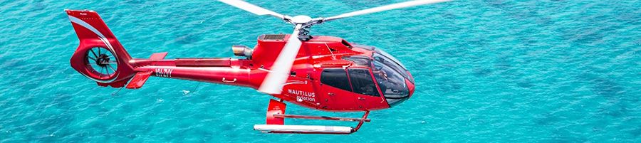 Nautilus Aviation Red Helicopter flying over the Great Barrier Reef