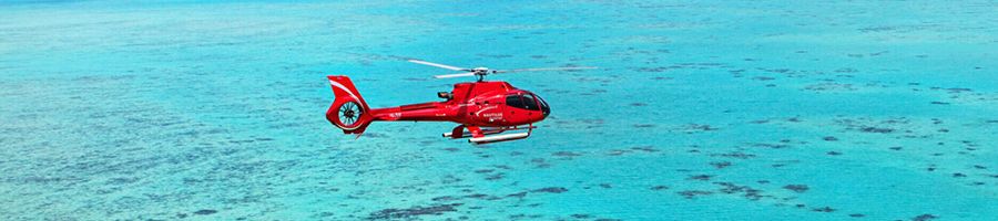Red helicopter flying over the turquoise reef