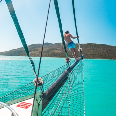 Man on the bow of a boat in the nets on a sunny day sailing