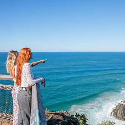 Two women at the Byron Bay lighthouse pointing out to sea