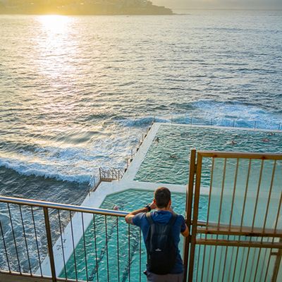 A person taking a photo of the ocean and iceberg pool at sunset