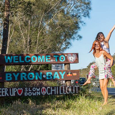 Two women in front of the Welcome to Byron Bay sign
