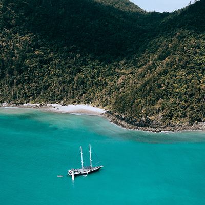 A big sailing vessel in the Whitsundays in blue water next to an island