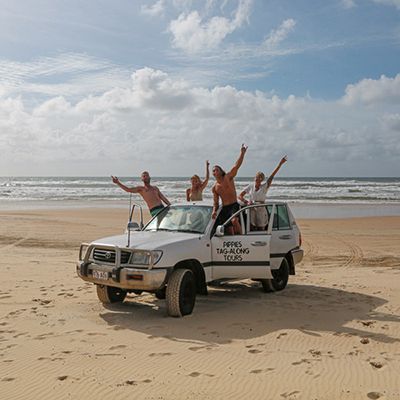 Four people on a 4WD on the beaches of K'gari