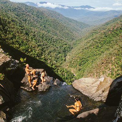 A group of backpackers swimming in a pool with forest in the background