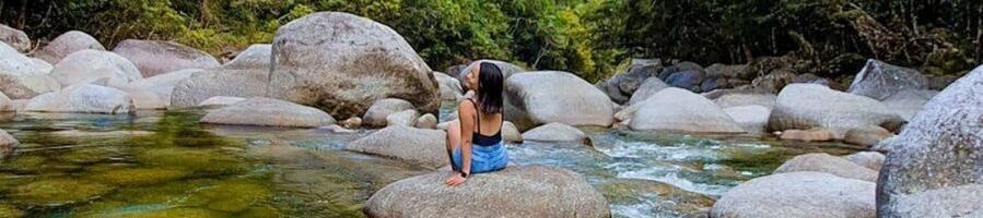 A woman sitting on a rock at Mossman Gorge