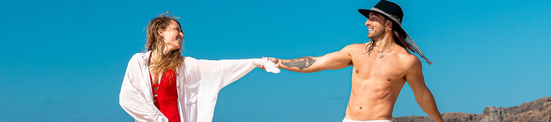 A man and woman holding hands at the beach