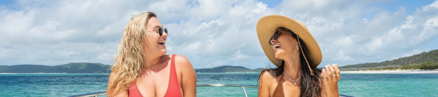 Two women in swimwear laughing at each other on a boat