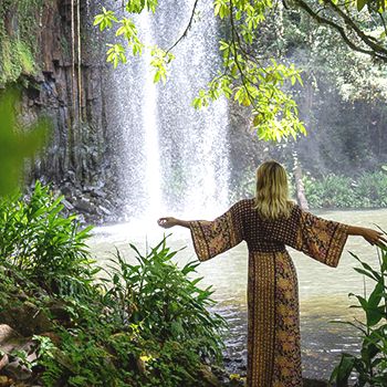 Millaa Millaa Falls, Atherton Tablelands with green forest surrounds and a woman in a flowy dress