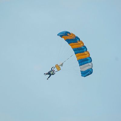 A travellers skydiving with a big yellow and blue parachit