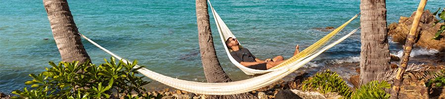 man lying in a hammock on a tropical island