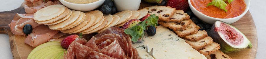 A platter of food with crackers, dips, cheese and grapes