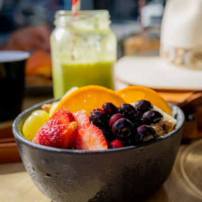 Close up bowl of fruit with smoothie in background