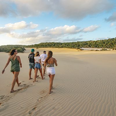 group of travellers walking on sand dunes at k'gari