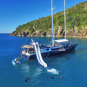 A maxi yacht in the Whitsunday Islands with blue ocean and a mega slide