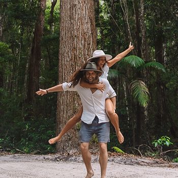 Two travellers playing around in the forest in white hats