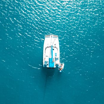 A drone shot of a white catamaran in bright blue water Whitsundays