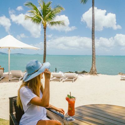 Girl drinking a cocktail on the beach near palm trees
