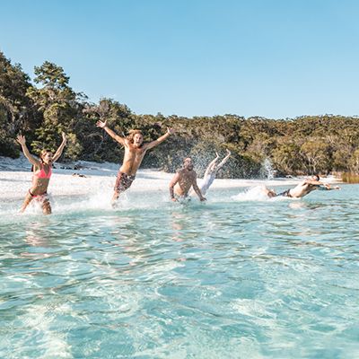 group jumping into Lake McKenzie's blue waters