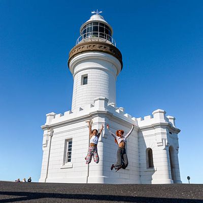 girls jumping in front of byron bay lighthouse